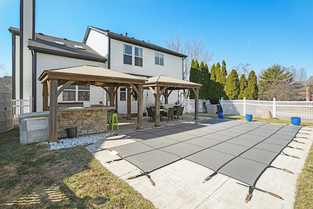 rear view of property with a gazebo, a fenced backyard, outdoor dry bar, and a patio