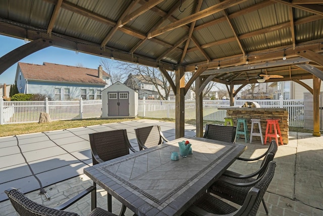 view of patio / terrace featuring a gazebo, a storage unit, an outbuilding, and outdoor dining area