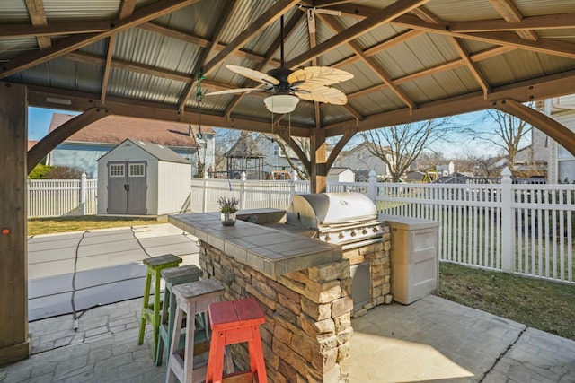 view of patio / terrace with a gazebo, a storage shed, a fenced backyard, an outbuilding, and an outdoor kitchen