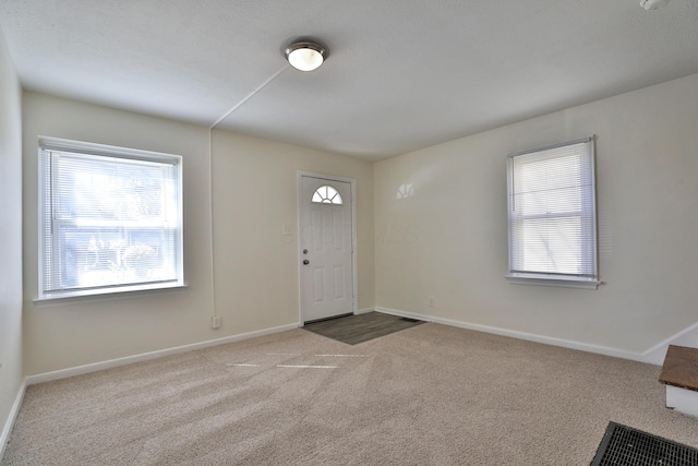 carpeted foyer with baseboards