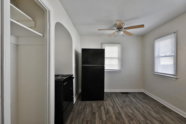 kitchen with baseboards, dark wood finished floors, arched walkways, black appliances, and a ceiling fan