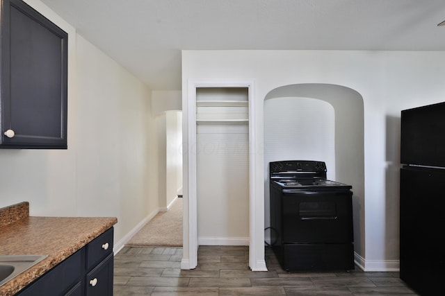 kitchen featuring baseboards, black appliances, and wood finish floors