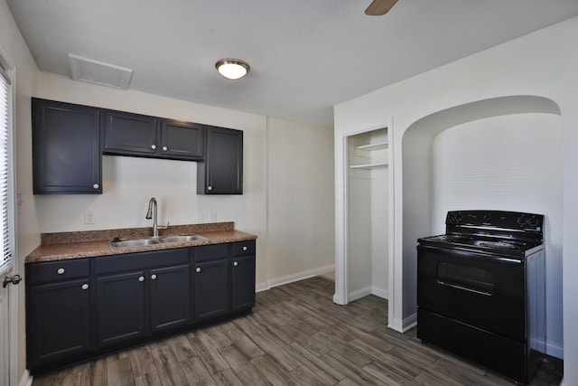 kitchen featuring dark wood-type flooring, a sink, dark countertops, black range with electric cooktop, and ceiling fan