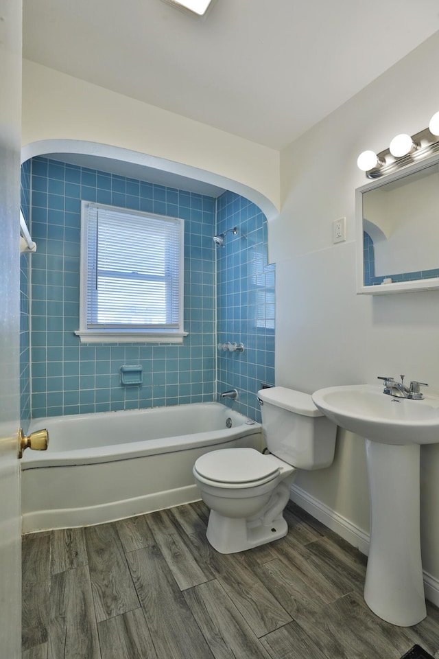 full bath featuring baseboards, shower / washtub combination, toilet, wood finished floors, and a sink