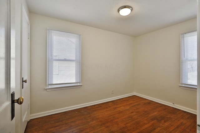 empty room with a wealth of natural light, baseboards, and wood-type flooring