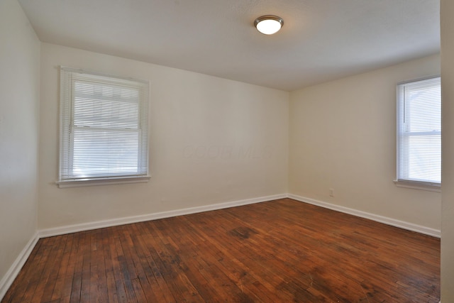 empty room featuring baseboards and dark wood-style flooring