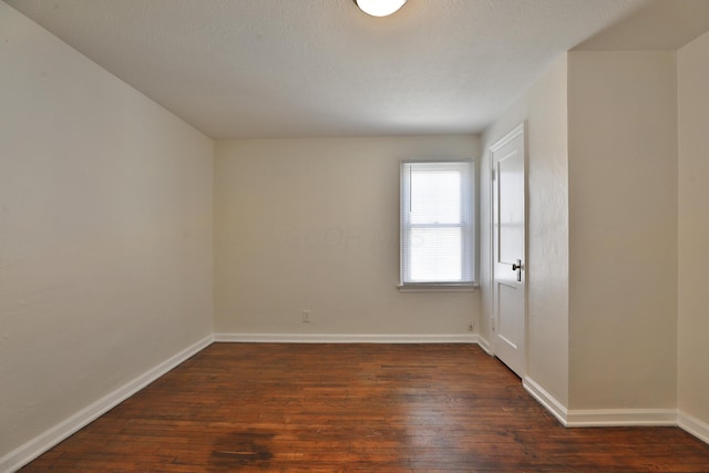 spare room with dark wood-style floors and baseboards