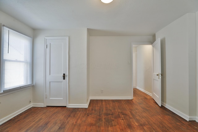 empty room featuring baseboards and wood-type flooring