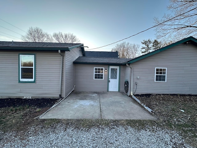 rear view of house with a patio area and roof with shingles