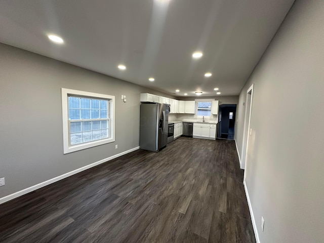 unfurnished living room featuring recessed lighting, baseboards, dark wood-style flooring, and a sink