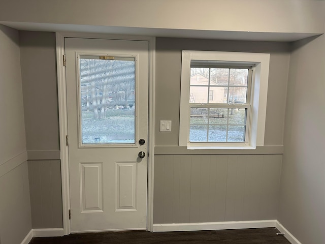 doorway to outside with baseboards, dark wood-style flooring, and wainscoting