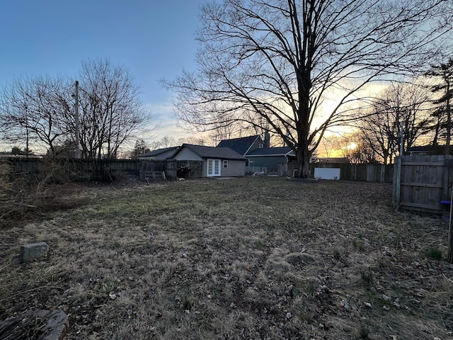 yard at dusk featuring a fenced backyard