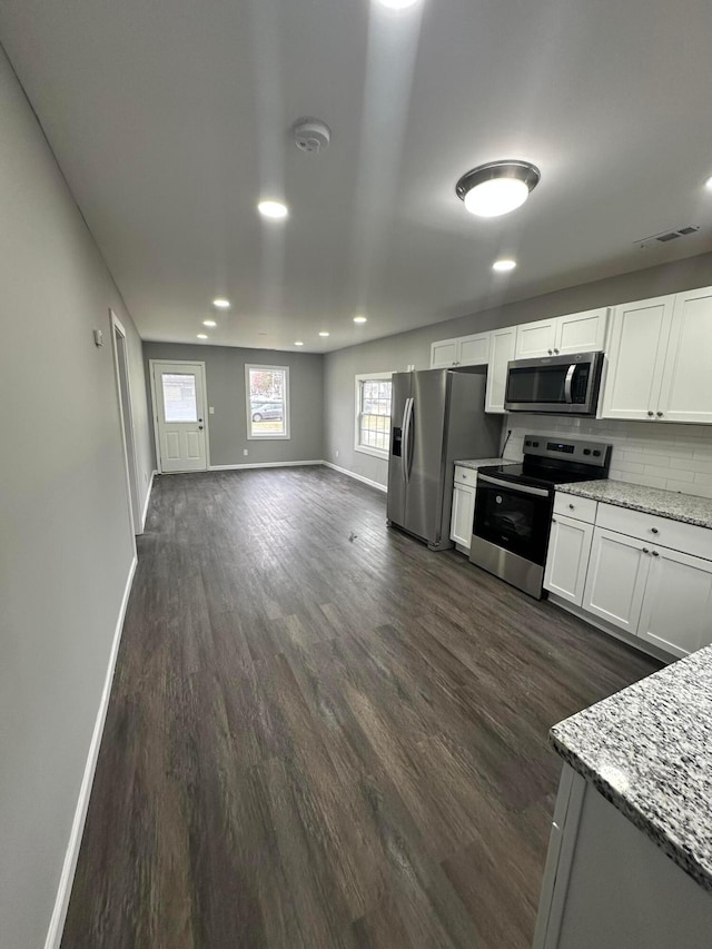 kitchen featuring visible vents, dark wood-type flooring, stainless steel appliances, decorative backsplash, and baseboards