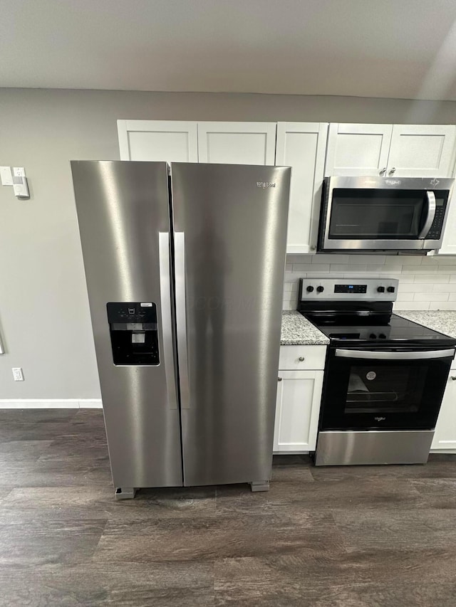 kitchen with stainless steel appliances, dark wood-style floors, decorative backsplash, and white cabinetry