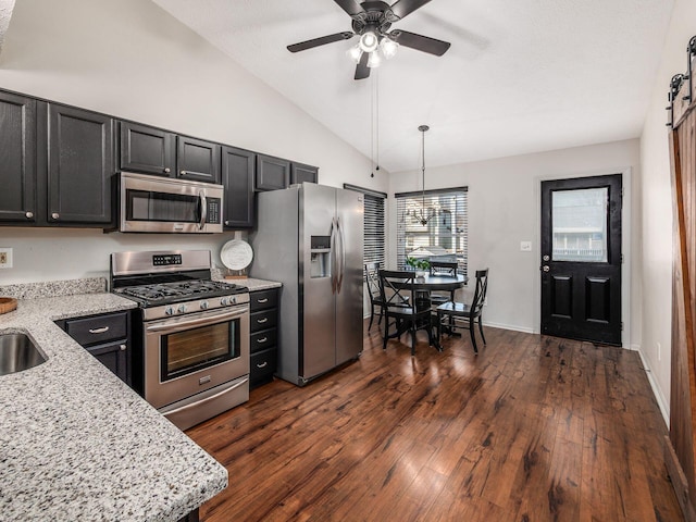 kitchen featuring dark cabinetry, light stone counters, dark wood-style floors, lofted ceiling, and appliances with stainless steel finishes