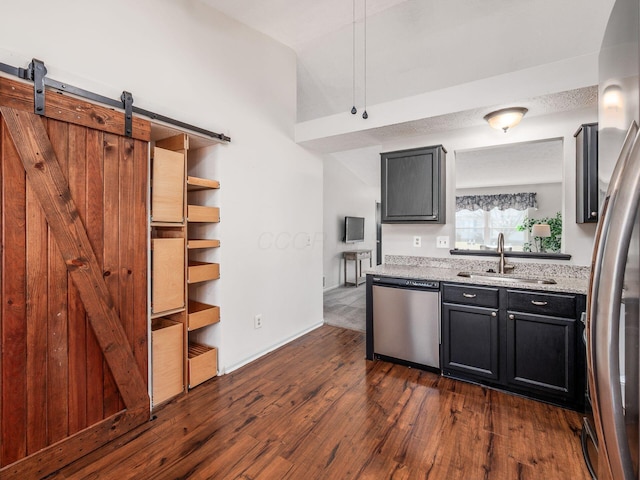 kitchen featuring a sink, dark wood finished floors, a barn door, appliances with stainless steel finishes, and dark cabinets