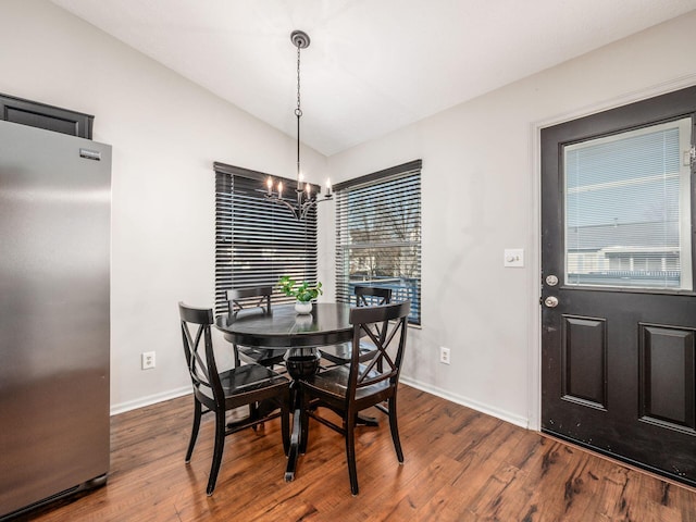 dining space featuring dark wood finished floors, baseboards, an inviting chandelier, and vaulted ceiling