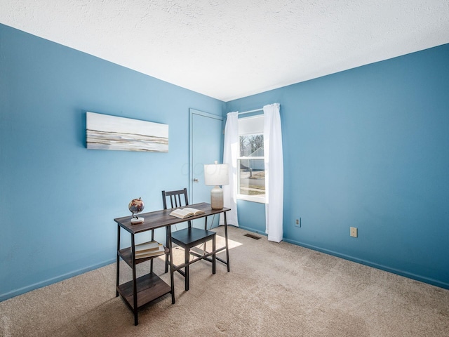 carpeted home office with visible vents, baseboards, and a textured ceiling