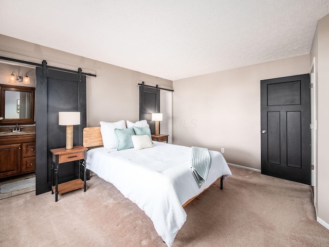 bedroom featuring a sink, a textured ceiling, a barn door, carpet, and baseboards