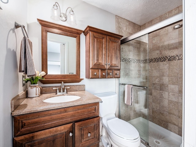 full bathroom with a shower stall, a textured ceiling, vanity, and toilet