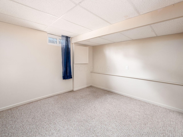 basement with baseboards, a paneled ceiling, and carpet floors