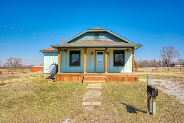 bungalow-style home featuring board and batten siding, a front lawn, covered porch, and a shingled roof