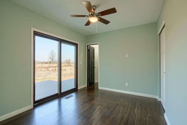 spare room with visible vents, baseboards, and dark wood-style floors