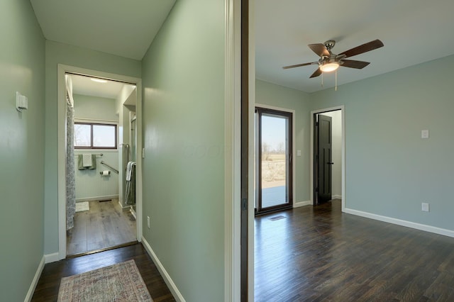 corridor with visible vents, baseboards, and dark wood-type flooring