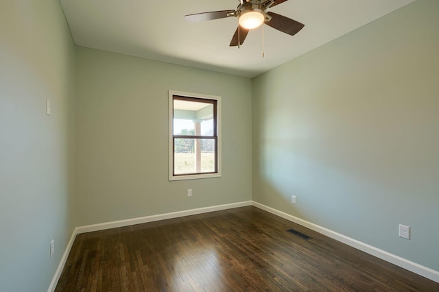 spare room featuring visible vents, baseboards, a ceiling fan, and dark wood-style flooring