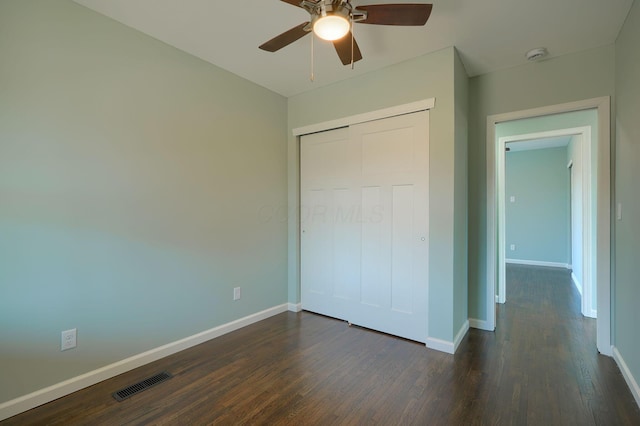 unfurnished bedroom featuring dark wood finished floors, visible vents, a closet, and baseboards