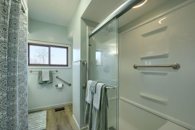 full bath with visible vents, wood finished floors, a stall shower, and baseboards