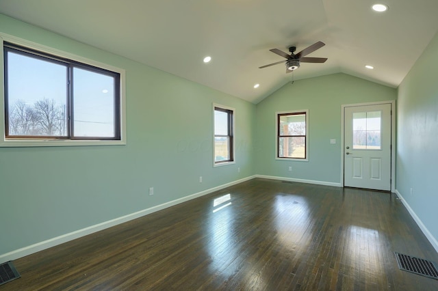 spare room with vaulted ceiling, dark wood-style floors, visible vents, and baseboards