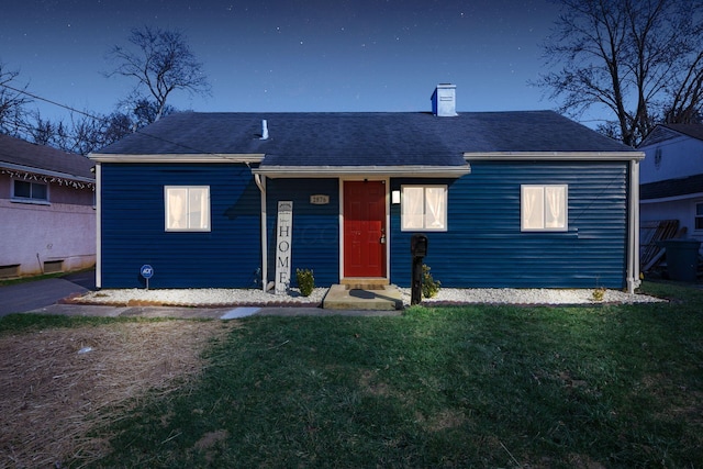 view of front of home featuring a front lawn, roof with shingles, and a chimney