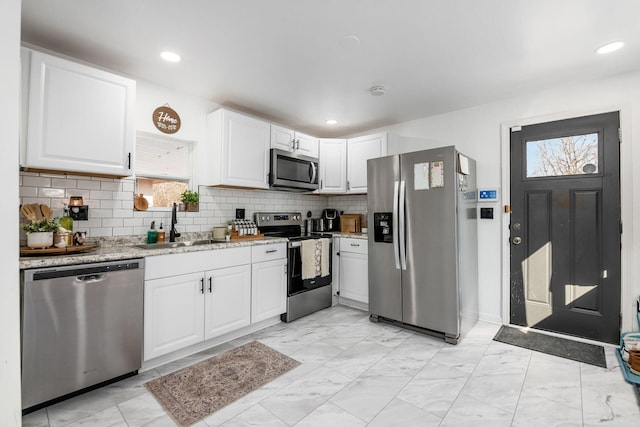 kitchen with marble finish floor, a sink, light stone counters, white cabinetry, and appliances with stainless steel finishes