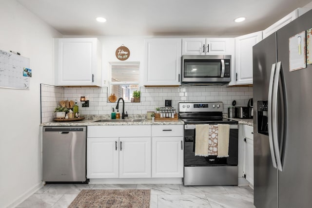 kitchen with a sink, stainless steel appliances, marble finish floor, and white cabinetry