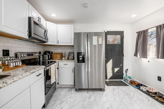 kitchen featuring backsplash, light stone countertops, appliances with stainless steel finishes, white cabinets, and marble finish floor