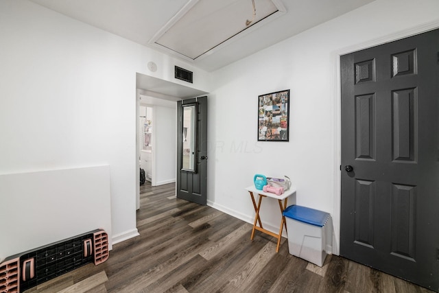 hall with visible vents, attic access, dark wood-type flooring, and baseboards