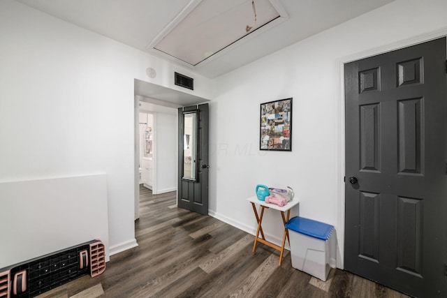 hallway featuring visible vents, baseboards, attic access, and dark wood-style flooring