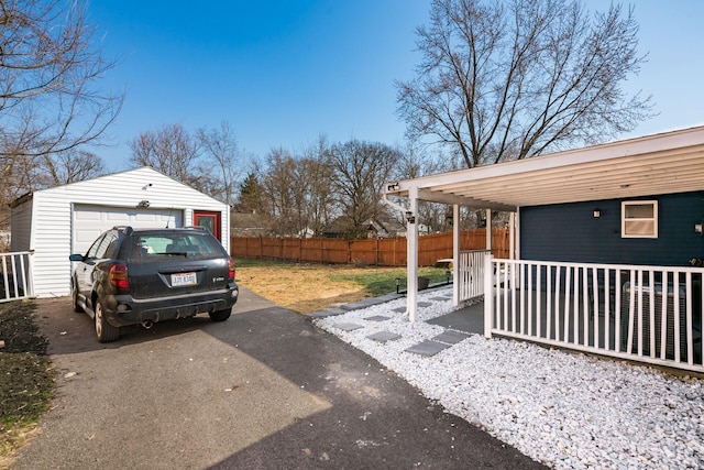 view of yard with a detached garage, fence, driveway, and an outdoor structure