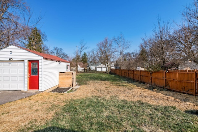 view of yard with a garage, driveway, an outdoor structure, and fence