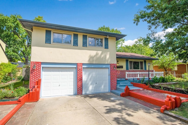 tri-level home with stucco siding, brick siding, an attached garage, and driveway