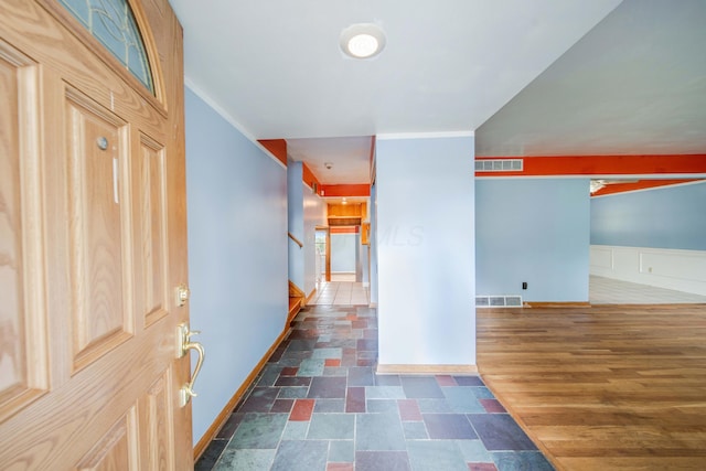 hall with stairs, dark wood-type flooring, a wainscoted wall, and visible vents