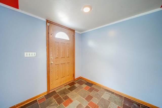 foyer entrance featuring stone finish flooring, baseboards, and ornamental molding