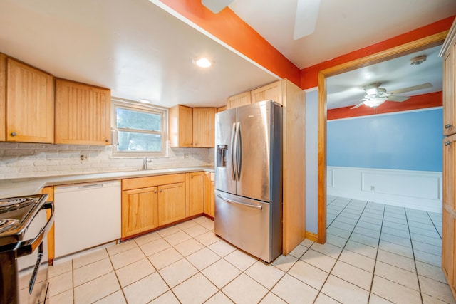 kitchen featuring light tile patterned floors, a wainscoted wall, ceiling fan, a sink, and appliances with stainless steel finishes