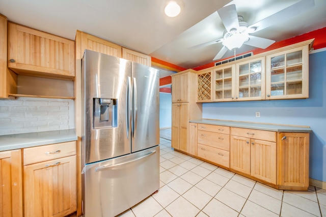 kitchen with light brown cabinetry, light tile patterned floors, stainless steel fridge, and light countertops