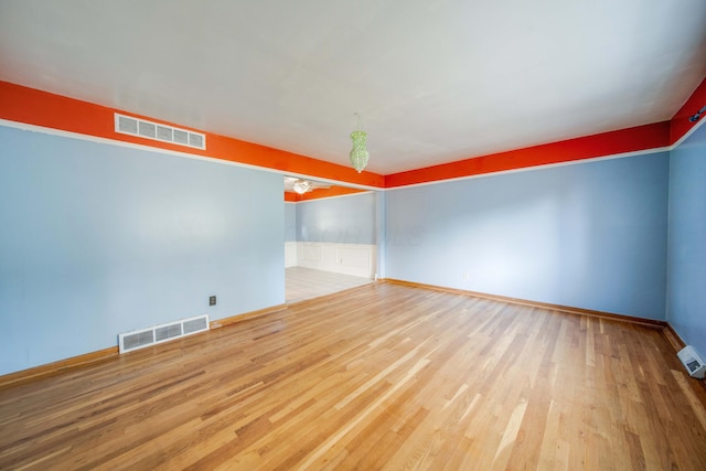 spare room with visible vents, baseboards, and wood finished floors