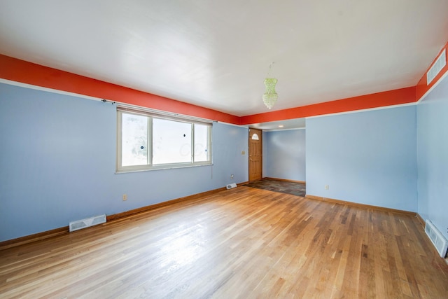 unfurnished room featuring visible vents, baseboards, and wood finished floors