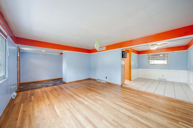 spare room with a wainscoted wall, wood finished floors, and visible vents