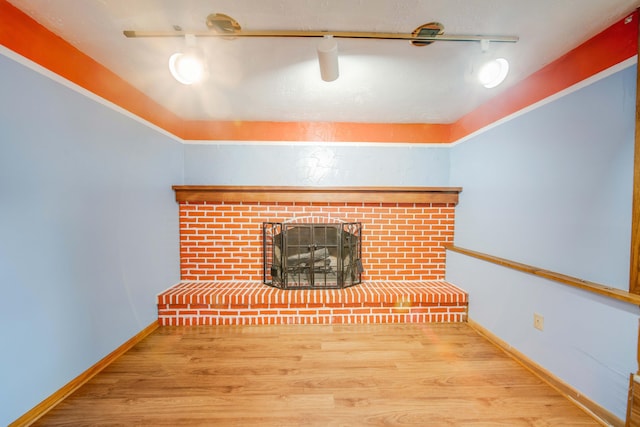 unfurnished living room with a fireplace, baseboards, and wood finished floors