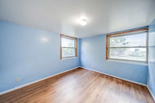 unfurnished room with wood finished floors, baseboards, and a textured wall